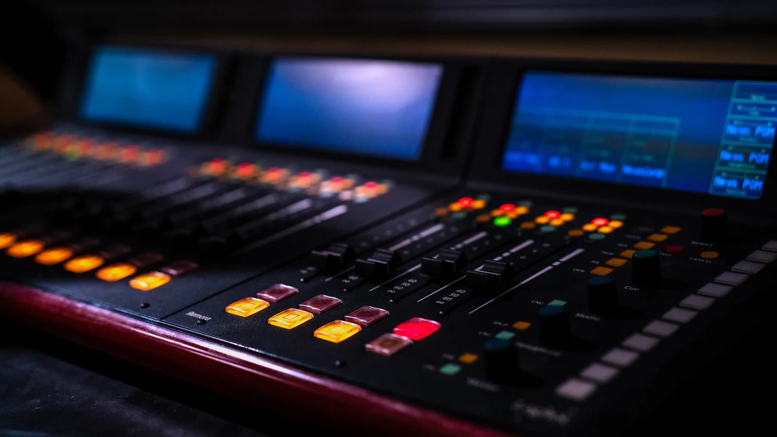 A broadcast mixing console with illuminated controls in a radio studio